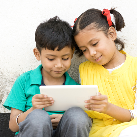 Two young Indian children looking at a tablet