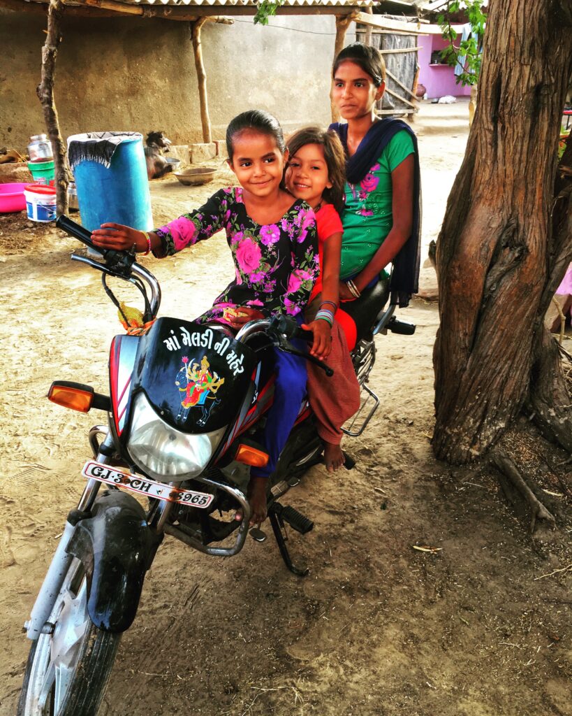 Three little girls on a static motorcycle in rural India